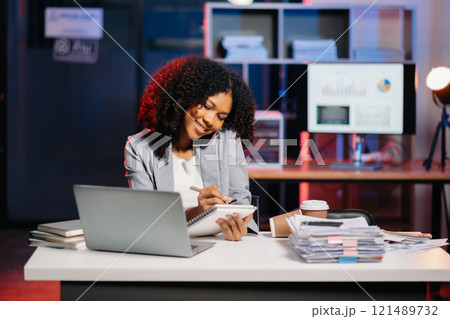 Business woman drinking coffee to get some energy for working overtime sitting at desk using computer and doing overtime project 121489732