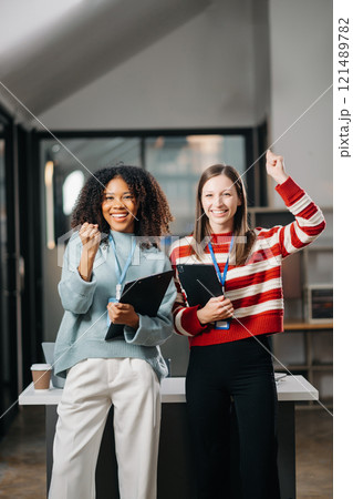 Businesswomen work and discuss their business plans. African women employee explains and shows her colleague the results paper in modern office. 121489782