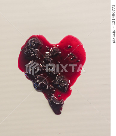 A heart-shaped spill of dark red jam on a light background . High quality photo 121490773