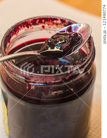A spoon dipped into a jar of homemade wild berry jam. High quality photo 121490774