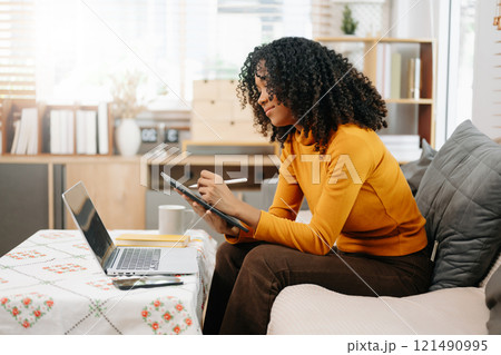 Young woman relax on comfortable couch at home texting messaging on smartphone and tablet 121490995