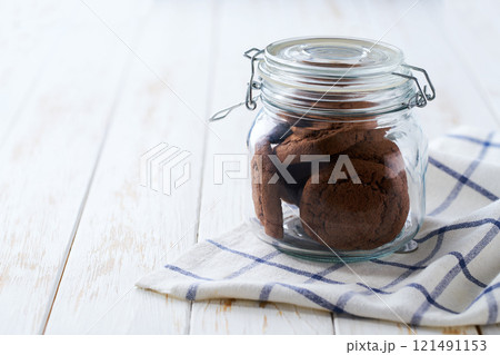 Chocolate brownie cookies in a jar, on a light kitchen table, with copy space for text. Chocolate brownie cookies in a jar, on a light kitchen table, with copy space for text. 121491153