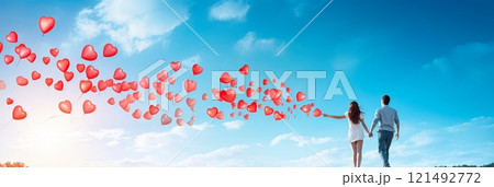Depict a joyful moment with a couple releasing heart-shaped balloons into a clear blue sky, symbolizing their love taking flight. 121492772