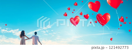 Depict a joyful moment with a couple releasing heart-shaped balloons into a clear blue sky, symbolizing their love taking flight. 121492773