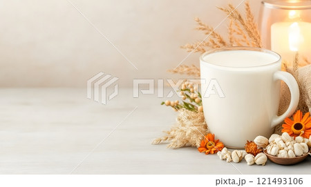 Steaming hot milk in a modern glass cup, placed near a glowing lamp and soft decor 121493106