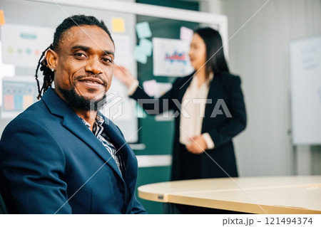 At a team meeting in the office, a black businessman, a CEO and leader, smiles with confidence. His business portrait captures leadership, diversity, and the essence of corporate success. At a team meeting in the office, a black businessman, a CEO and leader, smiles with confidence. His business portrait captures leadership, diversity, and the essence of corporate success. 121494374