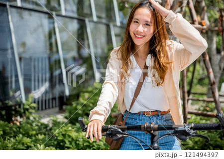 In the city a young woman shields from the hot sun on her bicycle embodying the beauty of outdoor fun and fashion. This season of happiness is all about freedom and relaxation. 121494397
