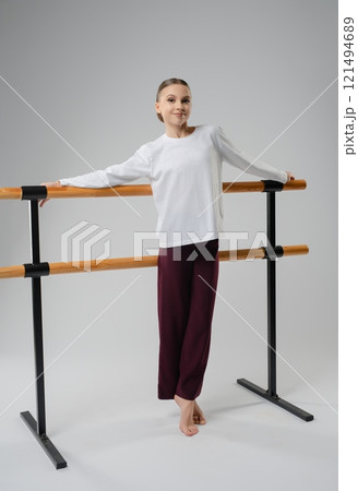 Girl practicing dance poses at a ballet barre during a studio session 121494689