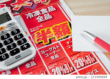 新聞折り込みチラシを見ながら特売品をメモするイメージ 121494694