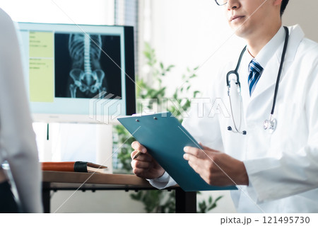 問診行う男性ドクターと腰のあたりを抑える女性患者 問診行う男性ドクターと腰のあたりを抑える女性患者 121495730