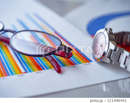テーブルに置かれたグラフとメガネと腕時計 121496441