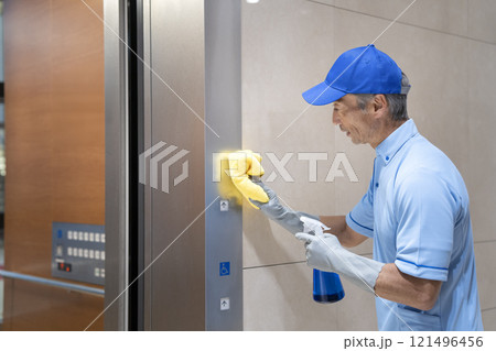 ビル清掃イメージ エレベーターのボタンを拭くシニアの男性清掃スタッフ ビル清掃イメージ エレベーターのボタンを拭くシニアの男性清掃スタッフ 121496456
