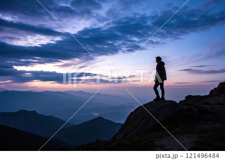An image of a person standing on a mountaintop at dusk 121496484