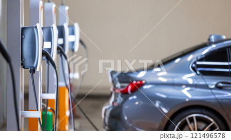 EV charger and electric car, Electric car charger station for charge ev battery, Plug for vehicle with electric engine, EV charger clean energy, Charging point at car parking lot department store. EV charger and electric car, Electric car charger station for charge ev battery, Plug for vehicle with electric engine, EV charger clean energy, Charging point at car parking lot department store. 121496578