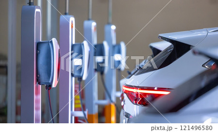 EV charger and electric car, Electric car charger station for charge ev battery, Plug for vehicle with electric engine, EV charger clean energy, Charging point at car parking lot department store. EV charger and electric car, Electric car charger station for charge ev battery, Plug for vehicle with electric engine, EV charger clean energy, Charging point at car parking lot department store. 121496580