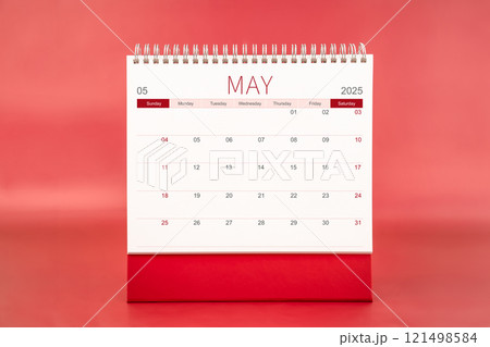May 2025 blank desk calendar on red color background. 121498584