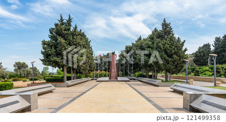The Turkish Martyrs Memorial in Baku, Azerbaijan, stands tall with Turkish and Azerbaijani flags waving in the breeze 121499358
