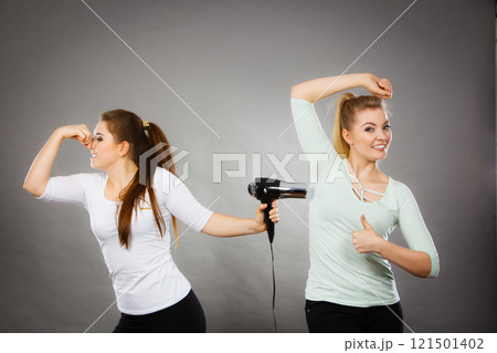 Woman drying friend armpit with hair dryer Woman drying friend armpit with hair dryer 121501402
