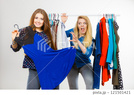Woman picking clothes in wardrobe, friend being jealous 121501421