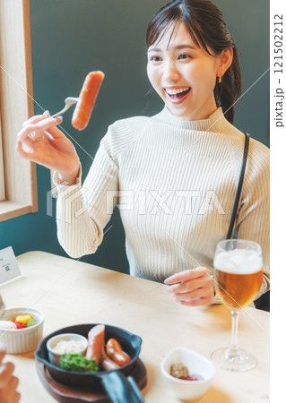 クラフトビールのおつまみにソーセージを食べる女性二人 121502212