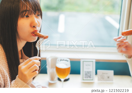 クラフトビールのおつまみにソーセージを食べる女性二人 クラフトビールのおつまみにソーセージを食べる女性二人 121502219