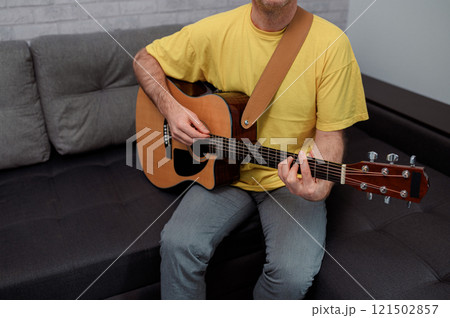 man guitarist playing guitar at home. Relaxing and sitting on sofa man guitarist playing guitar at home. Relaxing and sitting on sofa 121502857