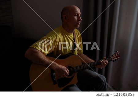 man guitarist playing guitar at home. Relaxing and sitting on sofa 121502858