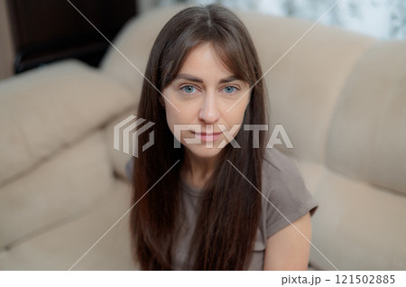 peace woman sitting comfortably on a gray couch at home, smiling and relaxing in soft natural light during the afternoon 121502885