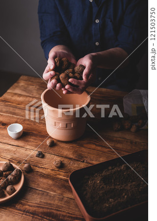Man Putting Clay Pebbles on the Bottom of Pot 121503750