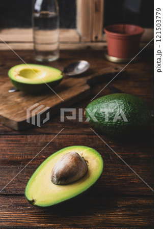 Green halved avocado on rustic kitchen table Green halved avocado on rustic kitchen table 121503779