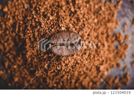 Coffee bean on heap of grinded coffee Coffee bean on heap of grinded coffee 121504019