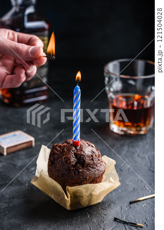 Hand lighting candle on birthday muffin 121504028