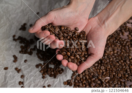 Man's hands holding fresh aromatic roasted coffee beans. Arabica and robusta blend. Wooden table and craft paper background 121504646