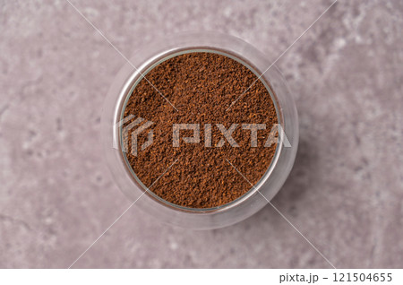 Top view closeup fresh aromatic ground coffee in a small glass on a gray concrete background 121504655