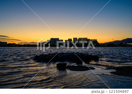 屋市のマンションがシルエットに沈む海辺の光景。西宮市香櫨園浜で撮影 121504897