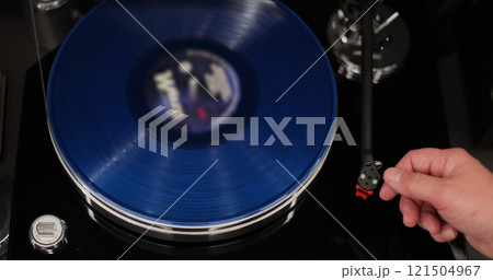 Male hands operating vinyl record player with a vinyl disc. The needle rises from a vintage vinyl record. The vinyl record is spinning. Male hands operating vinyl record player with a vinyl disc. The needle rises from a vintage vinyl record. The vinyl record is spinning. 121504967