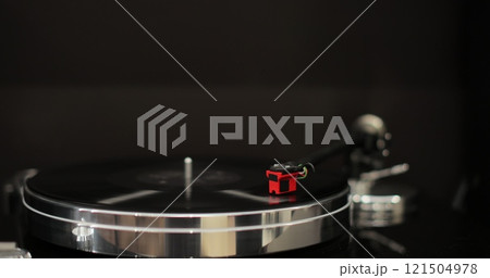Male hands operating vinyl record player with a vinyl disc. The needle rises from a vintage vinyl record. The vinyl record is spinning. Male hands operating vinyl record player with a vinyl disc. The needle rises from a vintage vinyl record. The vinyl record is spinning. 121504978