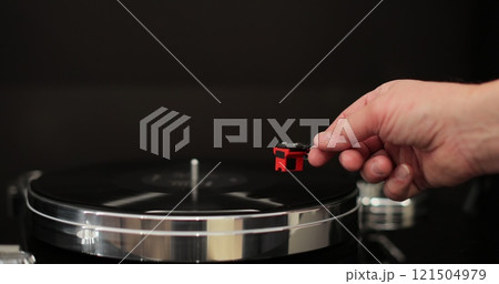 Male hands operating vinyl record player with a vinyl disc. The needle rises from a vintage vinyl record. The vinyl record is spinning. Male hands operating vinyl record player with a vinyl disc. The needle rises from a vintage vinyl record. The vinyl record is spinning. 121504979