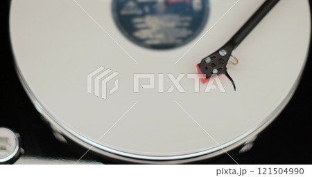 Close-up of a vinyl record spinning on a retro turntable from top view. Classic vinyl record player. Close-up of a vinyl record spinning on a retro turntable from top view. Classic vinyl record player. 121504990