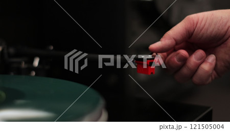 Male hands operating vinyl record player with a vinyl disc. The needle rises from a vintage vinyl record. The vinyl record is spinning. 121505004