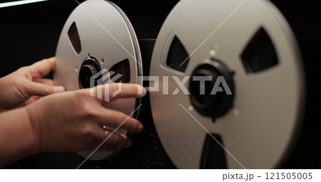 Man puts bobbins with tape onto a recorder. Bobbin tape recorder. Old vintage reel-to-reel player. Vintage tape recorder roller. Man puts bobbins with tape onto a recorder. Bobbin tape recorder. Old vintage reel-to-reel player. Vintage tape recorder roller. 121505005