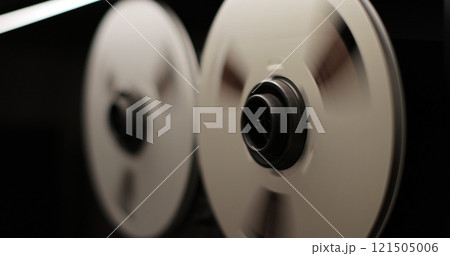 Reel to reel tape recorder playing. Rotating vintage music player close up. Retro tape. Old school concept. Reel to reel tape recorder playing. Rotating vintage music player close up. Retro tape. Old school concept. 121505006