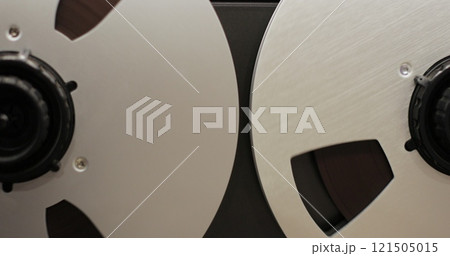 Reel to reel audio recorder tapes spinning. Rotating vintage music player close up. Retro tape. Old school concept. Reel to reel audio recorder tapes spinning. Rotating vintage music player close up. Retro tape. Old school concept. 121505015