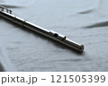 ダークな印象の白い布の上に置かれたフルートの頭部管のアップy 121505399