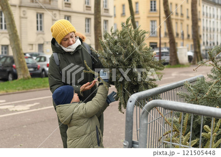 Mother and son throw away Christmas trees behind the fence Mother and son throw away Christmas trees behind the fence 121505448