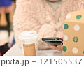 室内のオープンカフェでスマホを操作しながらコーヒーを楽しむ女性 121505537
