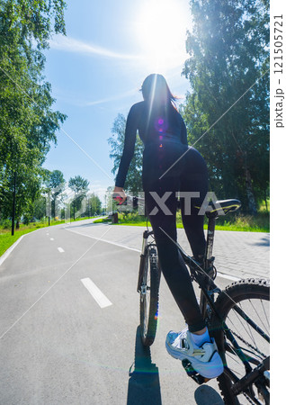 Rear view of Caucasian woman riding bike in park. Vertical photo. Rear view of Caucasian woman riding bike in park. Vertical photo. 121505721