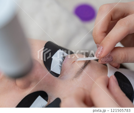 A specialist glues a client's drooping eyelid before eyelash extensions. A specialist glues a client's drooping eyelid before eyelash extensions. 121505783