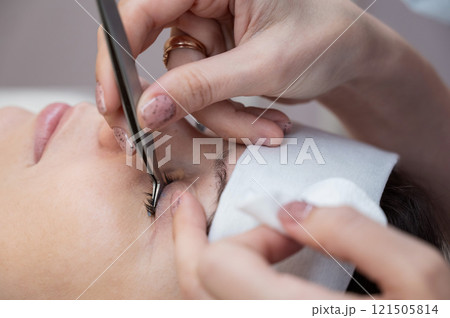 A master removes eyelash extensions from a client. A master removes eyelash extensions from a client. 121505814