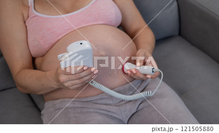 Close-up of a pregnant woman's belly using a home doppler. Normal baby heartbeat. Close-up of a pregnant woman's belly using a home doppler. Normal baby heartbeat. 121505880